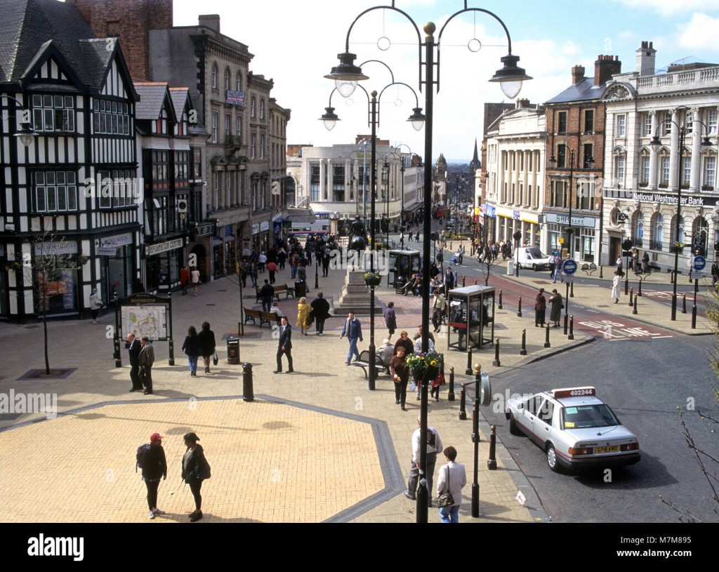 Queen Square and Wolverhampton city centre on a bright day: people in the square, historic timber-framed and stone buildings, and clear sky.